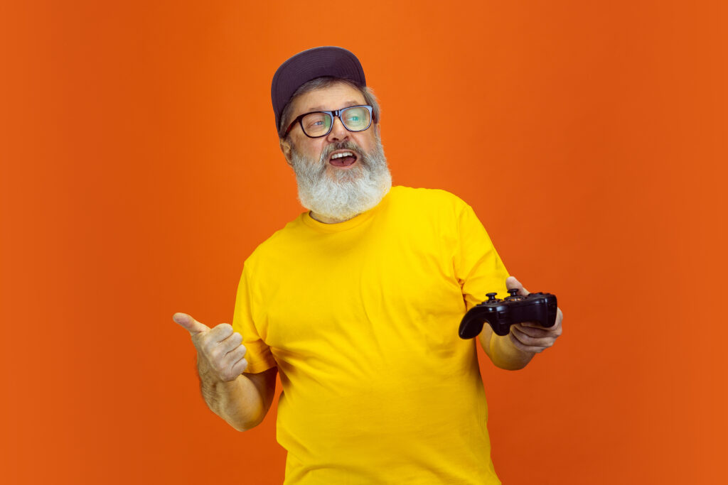 Homme senior avec une manette de jeux vidéo sur fond orange